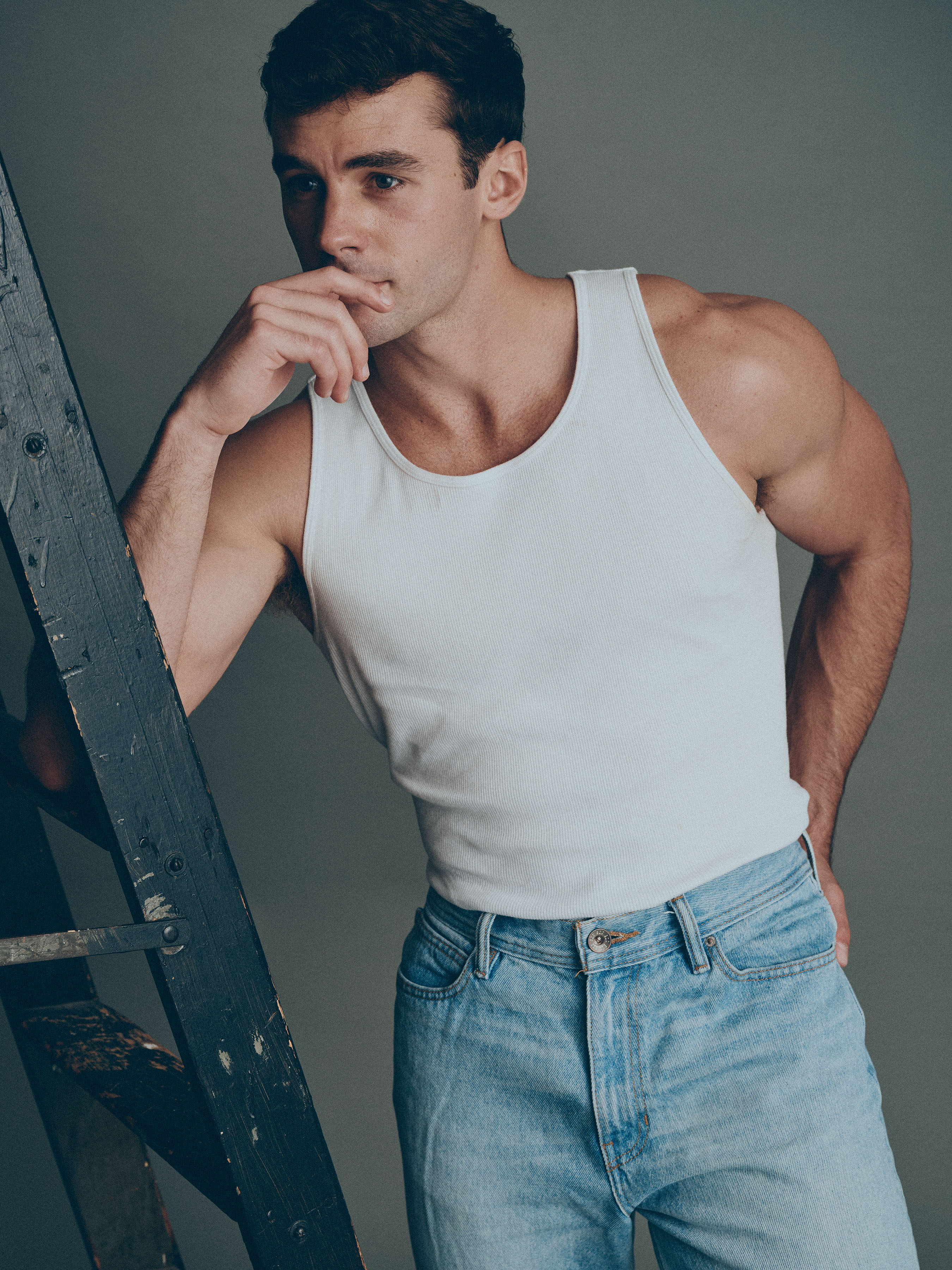 Jake_31_WEB Male model Jake wearing a white tank top and jeans, posed casually during a professional studio portfolio shoot